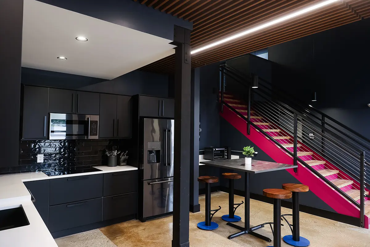 Modern industrial office breakroom in Greenwood Indiana with black cabinetry, wood accents, and bar seating