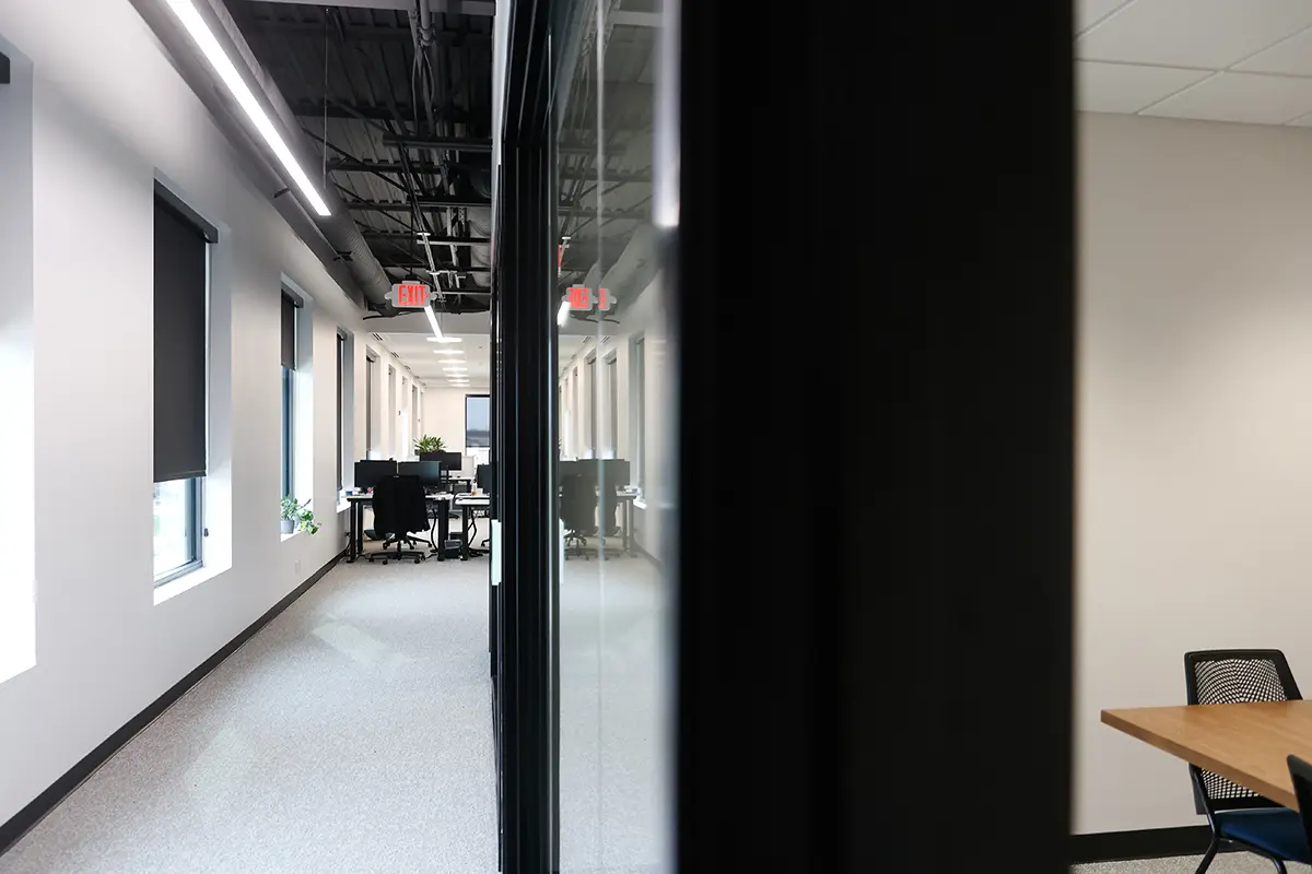 Office corridor leading to open workstations with natural light and modern workplace design in Fishers Indiana