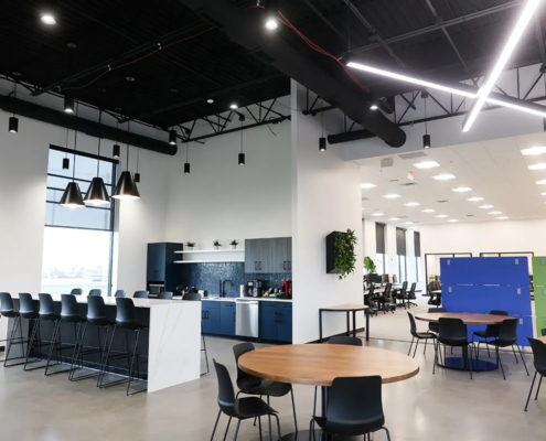 Modern office café and breakroom in Fishers Indiana with bar seating, pendant lighting, and open collaboration area