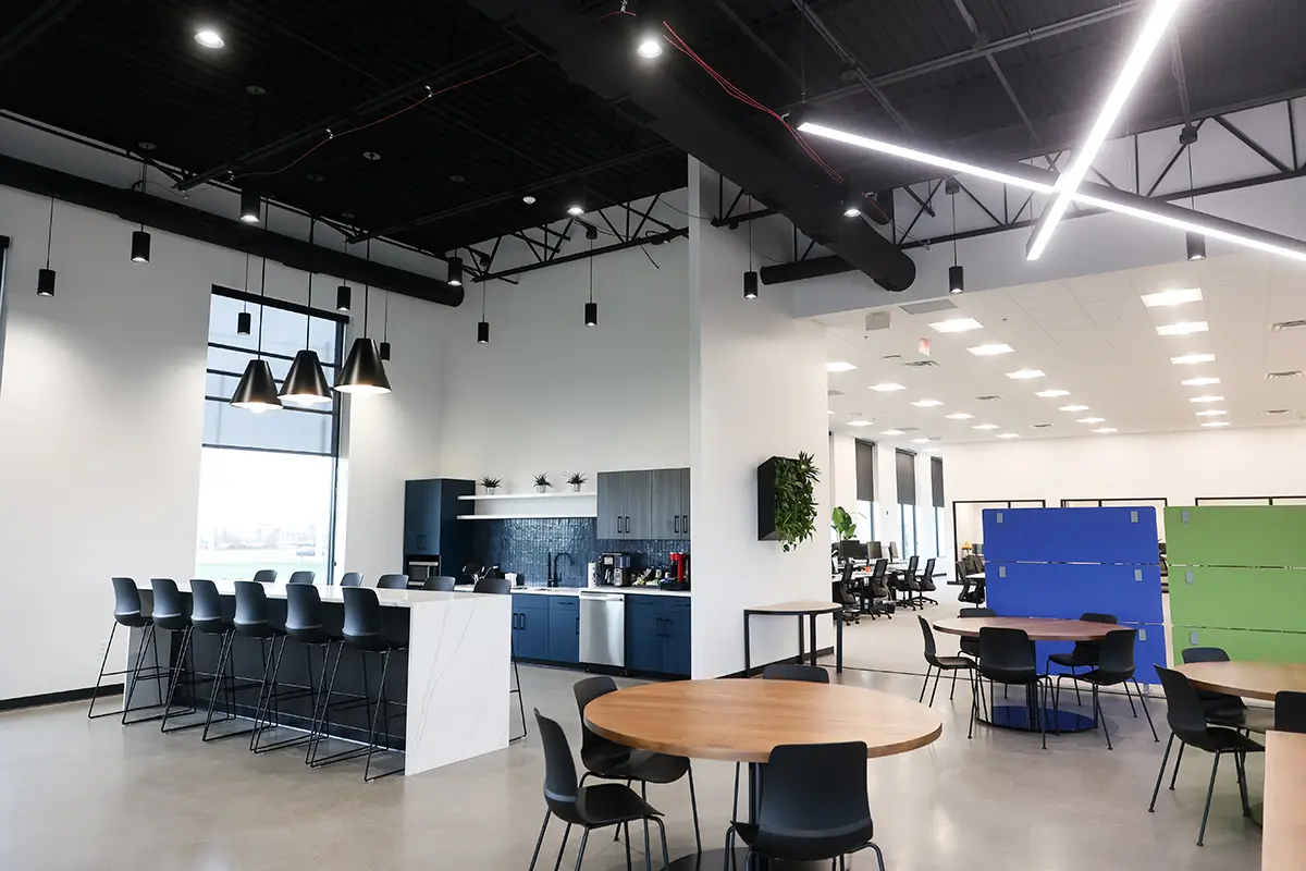 Modern office café and breakroom in Fishers Indiana with bar seating, pendant lighting, and open collaboration area