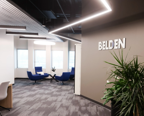 Modern collaborative workspace with blue lounge seating, large windows, and contemporary office lighting design