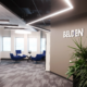 Modern collaborative workspace with blue lounge seating, large windows, and contemporary office lighting design