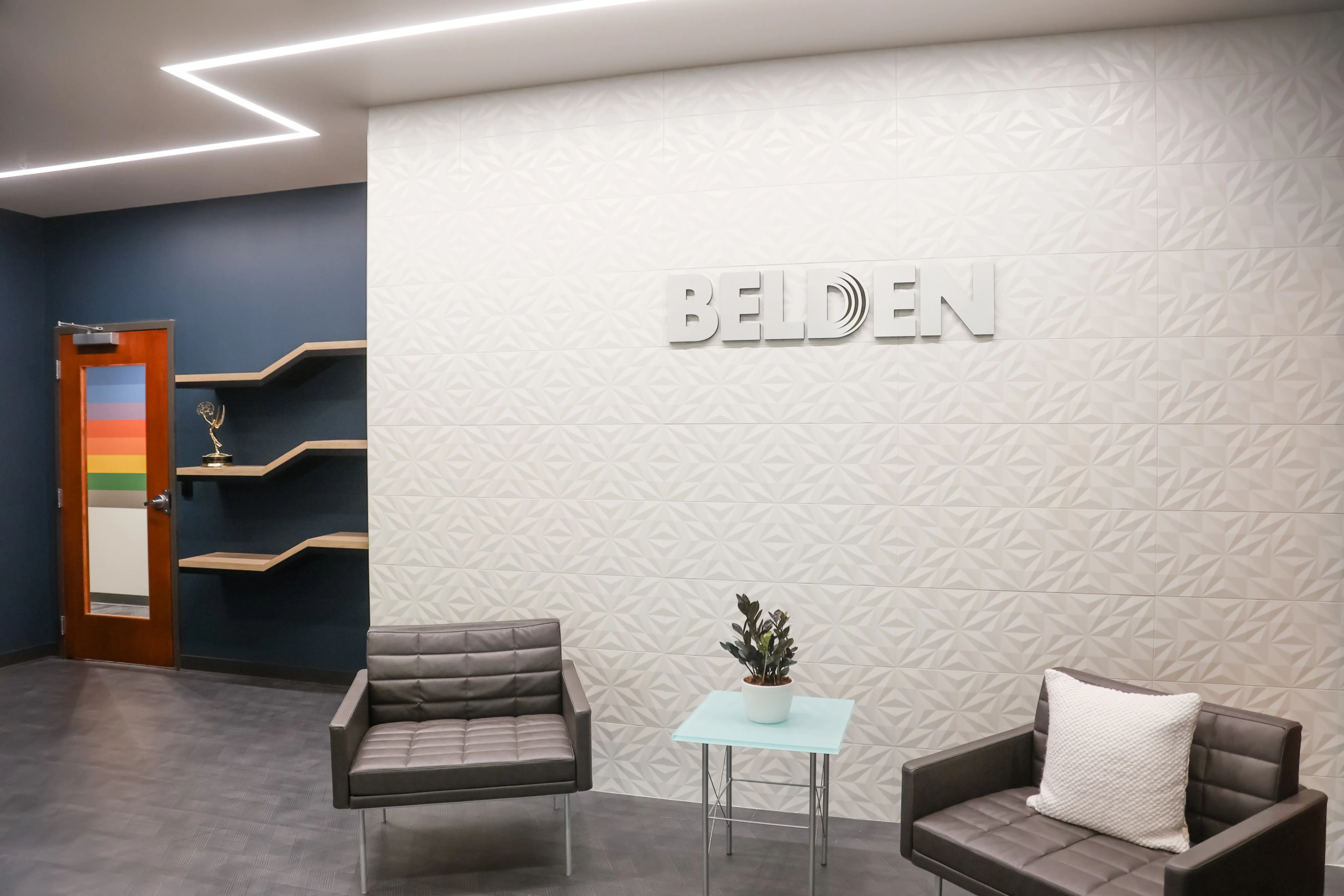 Branded office lounge with Belden feature wall, modern seating, and commercial interior design in Indianapolis