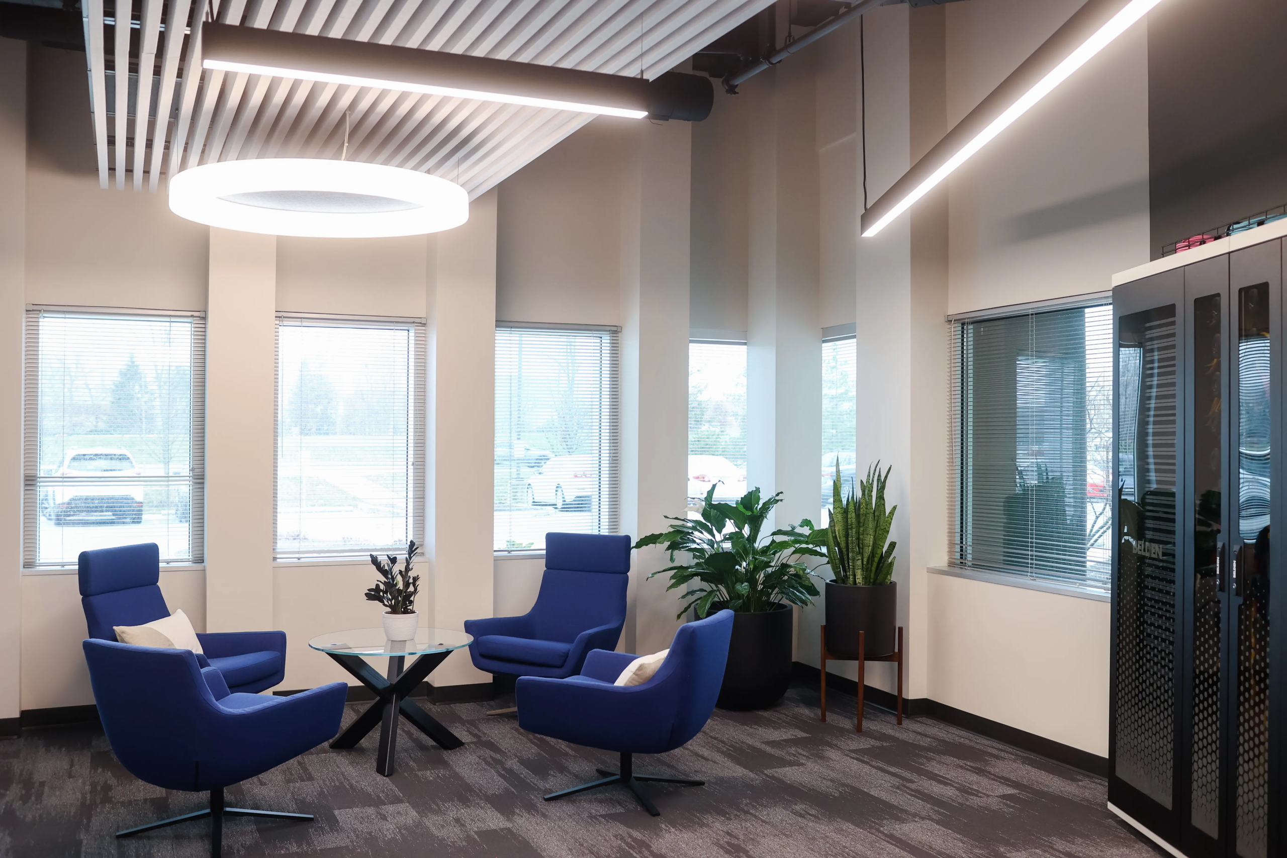 Office lounge with natural light, modern seating, and biophilic elements in commercial interior design project