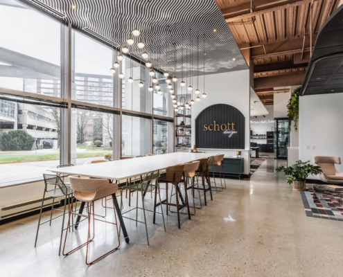 Commercial office collaboration space in Indianapolis, Indiana with large communal table, natural light, and modern lighting design