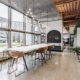 Commercial office collaboration space in Indianapolis, Indiana with large communal table, natural light, and modern lighting design