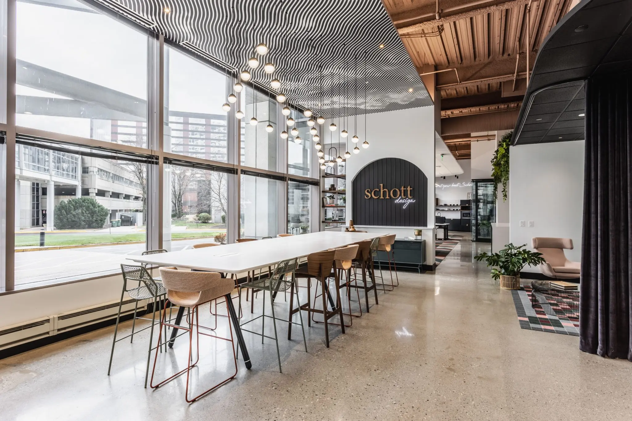 Commercial office collaboration space in Indianapolis, Indiana with large communal table, natural light, and modern lighting design