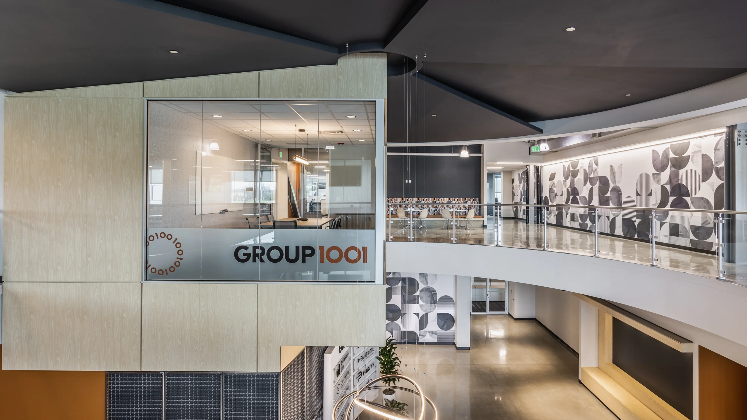 Glass conference room with Group 1001 branding overlooking modern office atrium