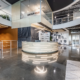 Main reception area in open atrium with curved desk, modern lighting, and polished concrete floors
