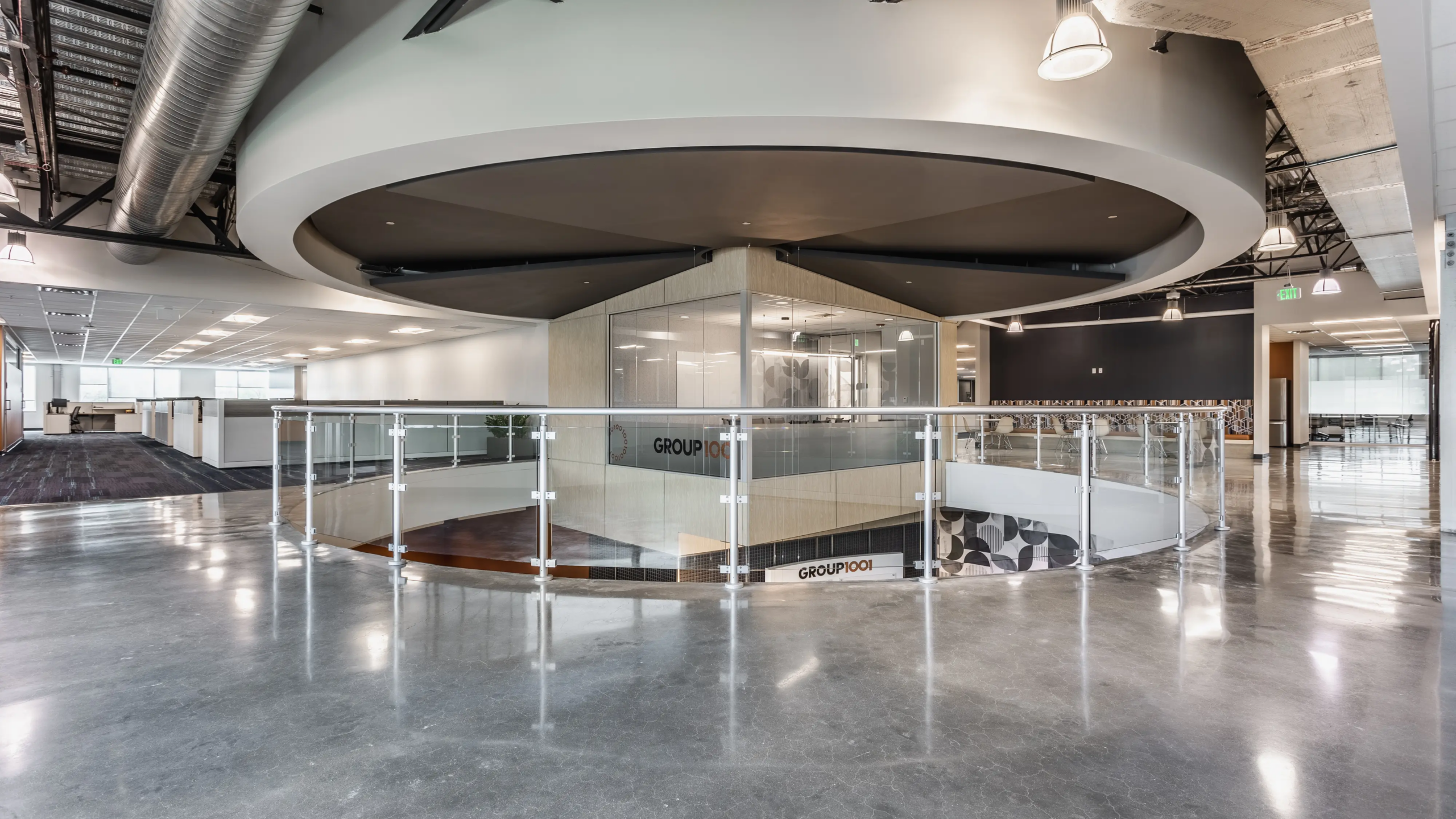 Open office atrium with glass railing, curved ceiling feature, and collaborative workspace