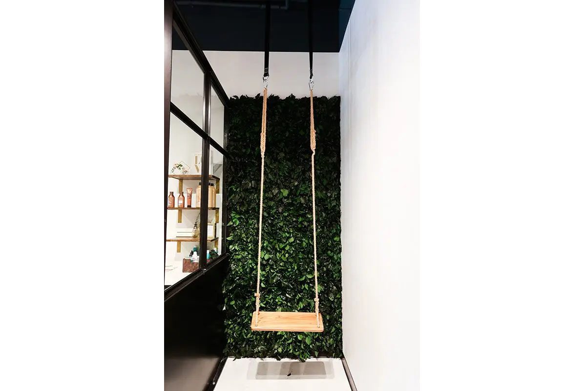 Interior feature in Carmel, Indiana with decorative swing installation and greenery wall for experiential design
