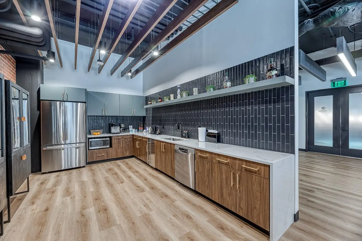 Office kitchen and breakroom design in Fishers, Indiana with wood cabinetry, tile backsplash, and modern appliances