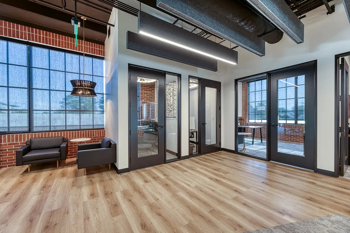 Modern office lounge in Fishers, Indiana with private offices, glass doors, and wood flooring