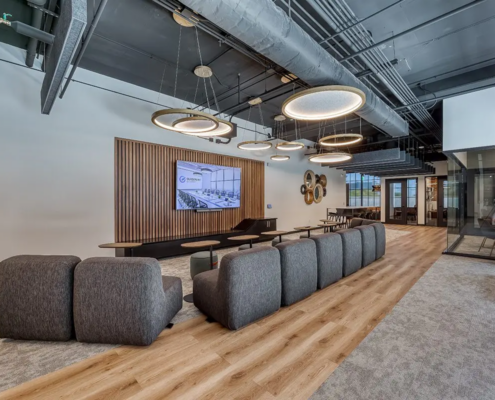 Open office lounge design in northern Indiana with soft seating, wood accents, and modern lighting fixtures