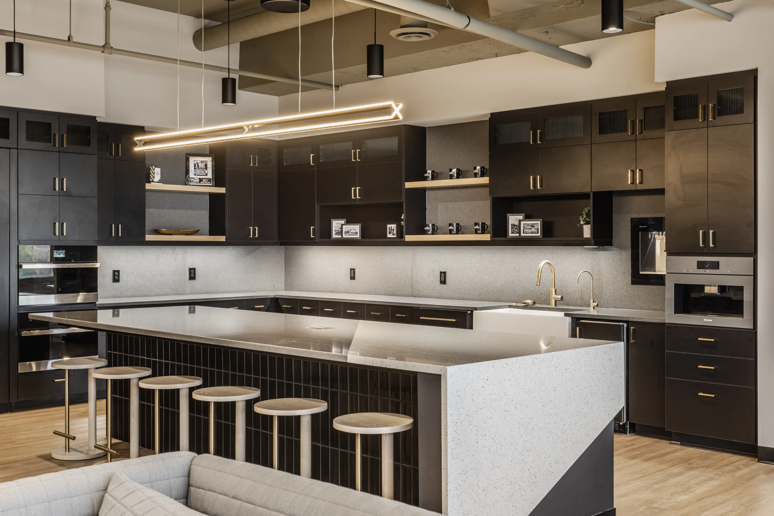 Modern office breakroom and kitchen design with large island seating and custom cabinetry at Pulte Carmel, Indiana