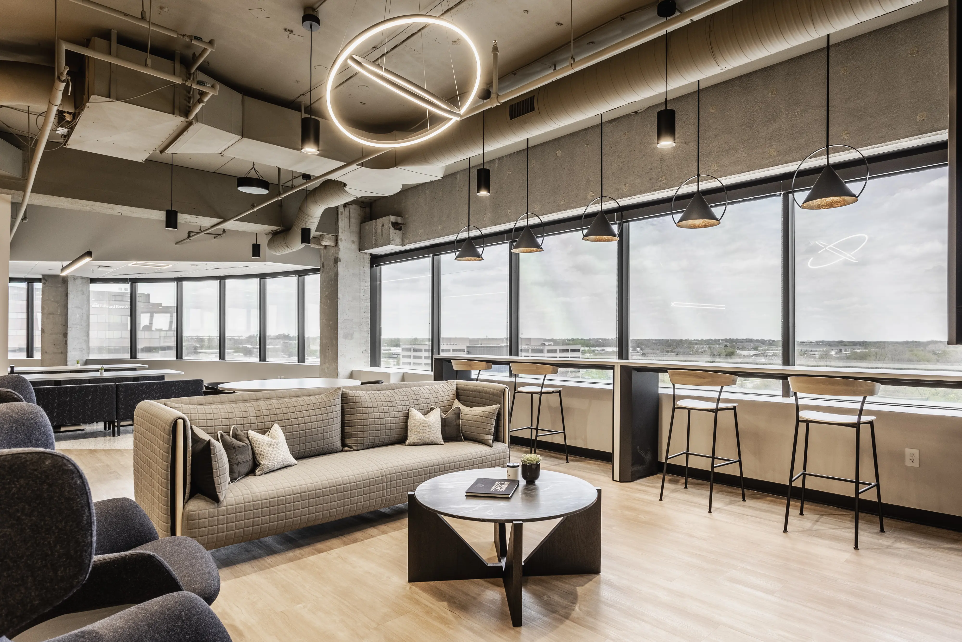 Open office lounge and collaboration space with modern seating and city views at Pulte Carmel