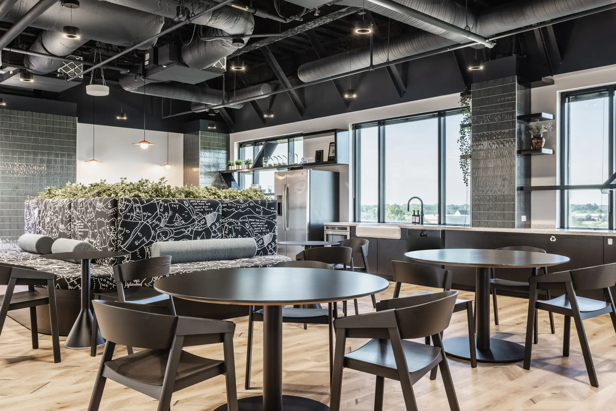 Office café in Fishers, Indiana with dining tables, booth seating, and open kitchen layout