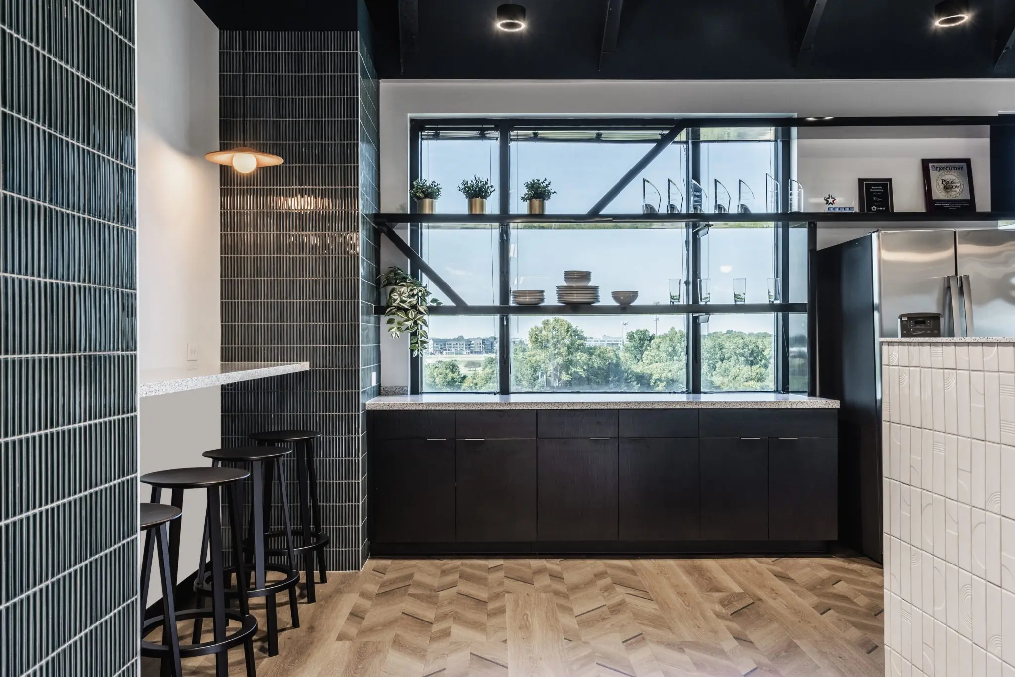 Open office lounge with bar seating in Fishers, Indiana featuring greenery accents and modern finishes