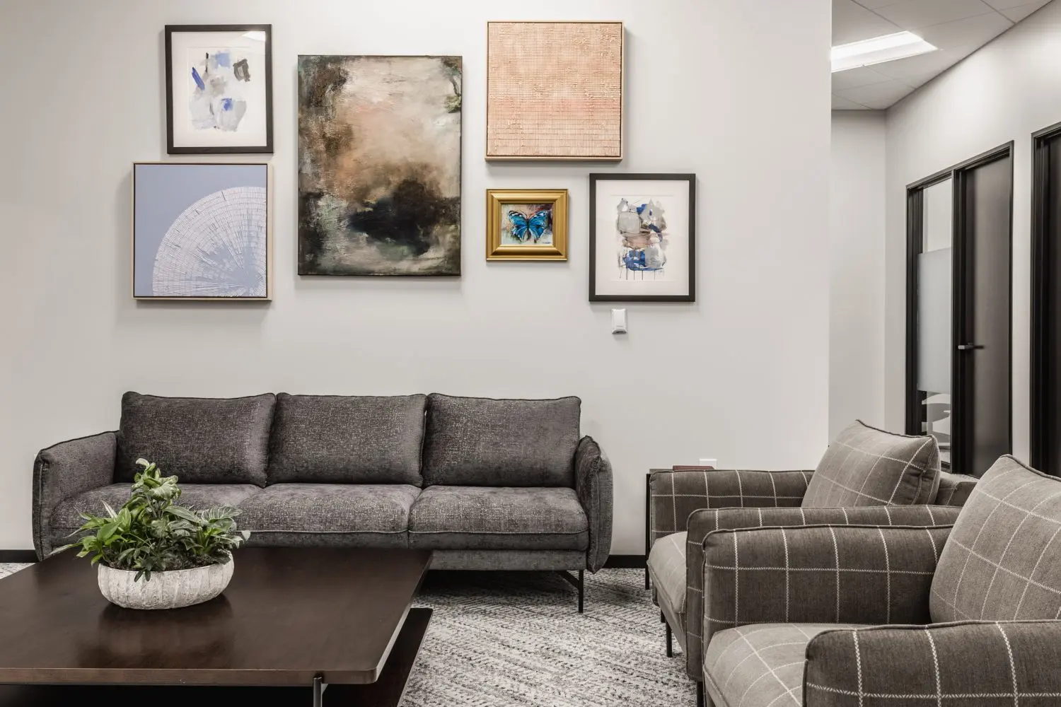 Modern office lounge in Indianapolis with upholstered seating, coffee table, and curated gallery wall artwork