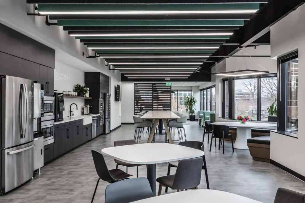 Modern office breakroom in Indianapolis, Indiana with kitchen, dining tables, and collaborative seating