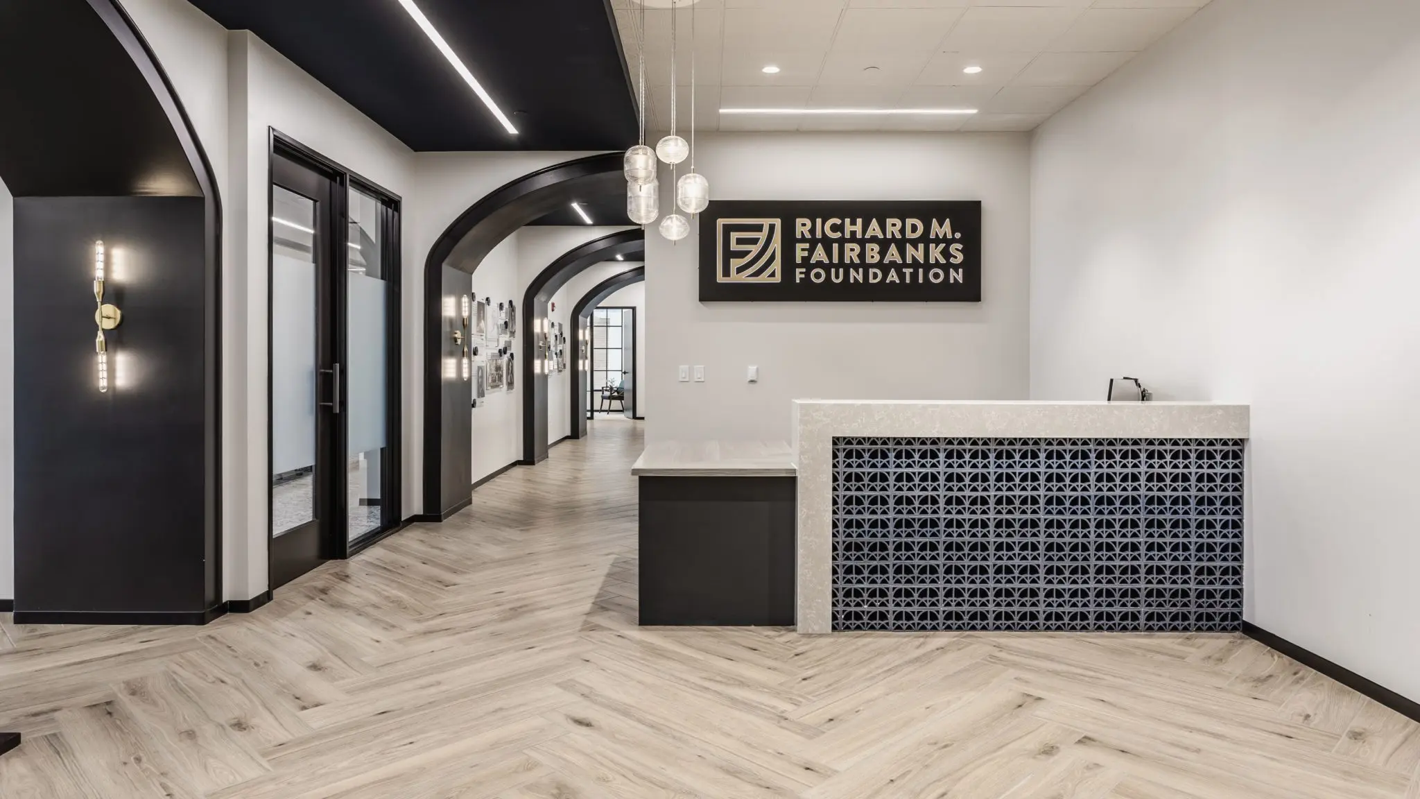 Office reception area in Indianapolis with branded signage, arched hallway, and custom desk design