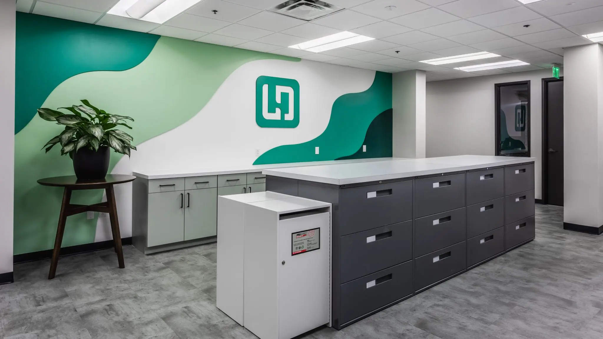 Office workroom in Indianapolis with storage cabinetry, work surfaces, and branded accent wall