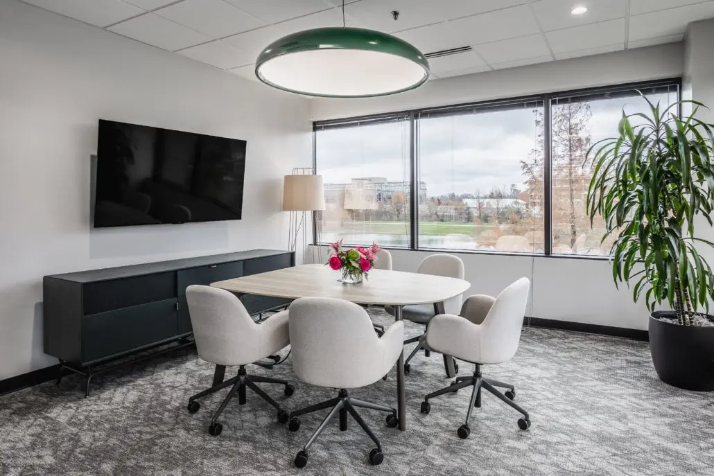 Small office meeting room in Indianapolis with round table, soft seating, and large windows