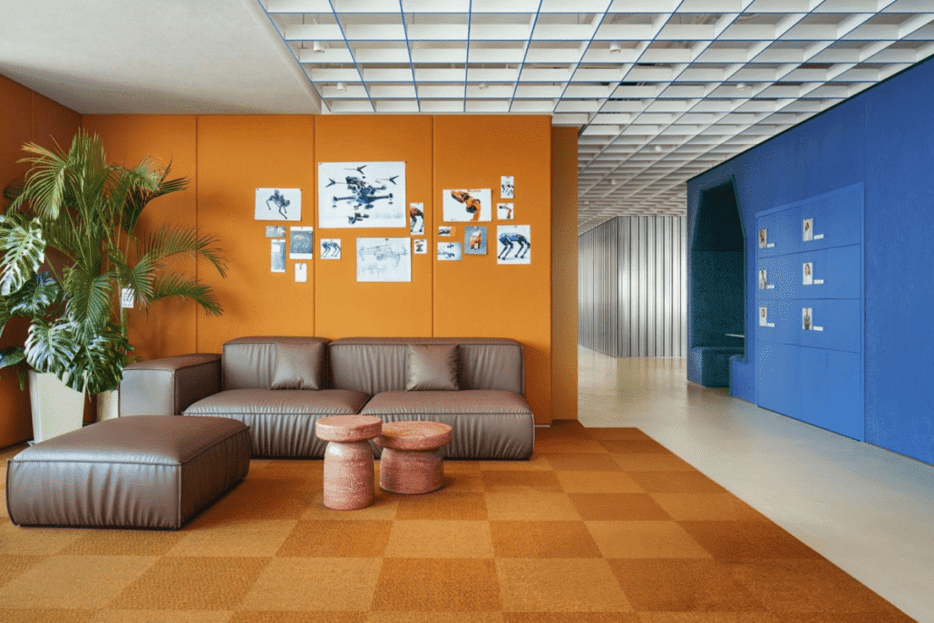 Creative office lounge with bold orange and blue walls, casual seating, and collaborative atmosphere