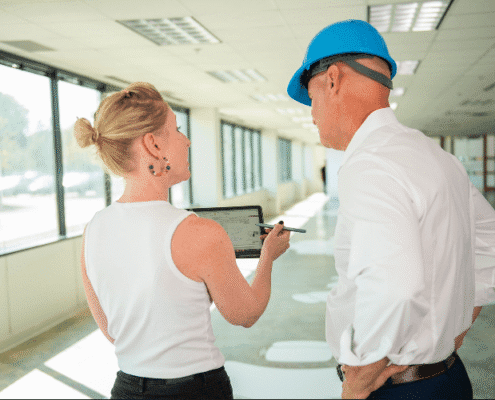Team reviewing office renovation plans during a construction walkthrough in a commercial space