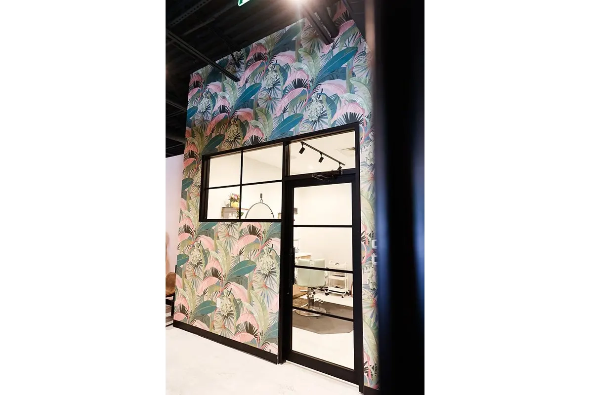 Salon entry in Carmel, Indiana with bold floral wallpaper, glass door, and modern interior design
